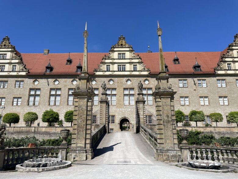 ロマンチック街道沿いにある街の「ヴァイカーイスハイム城」の美しいオレンジの屋根と庭園