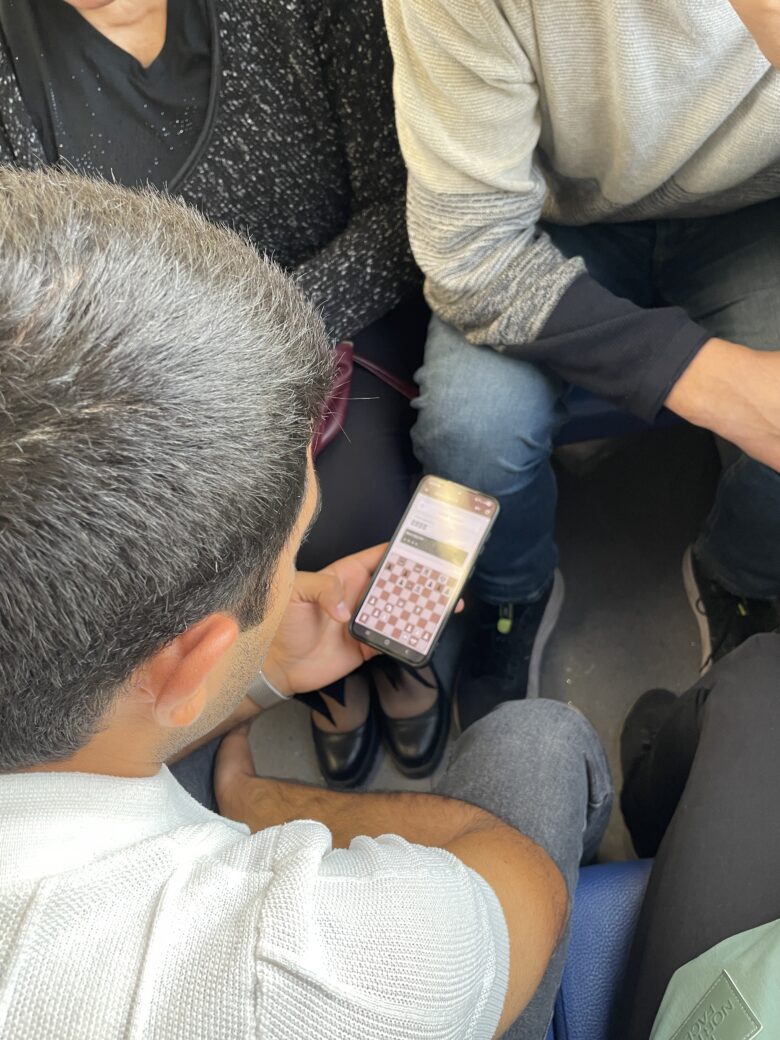 電車の中でオンラインチェスをする若者