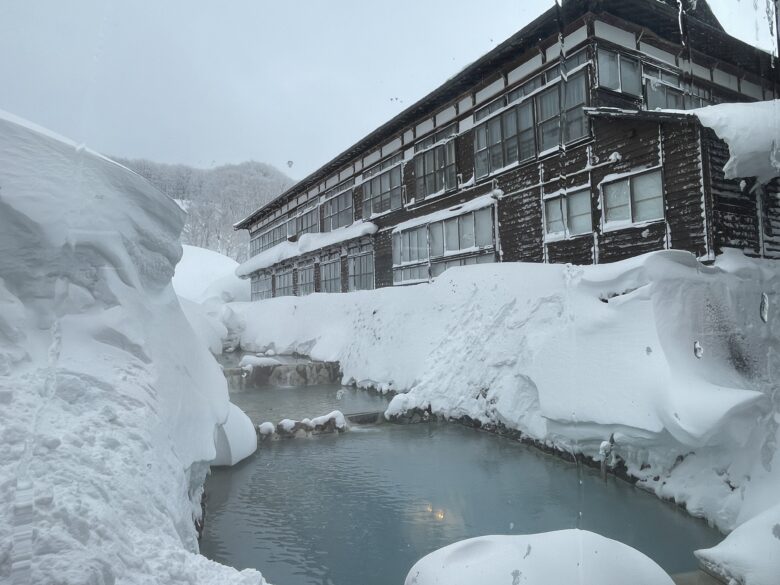豪雪地帯にある酸ヶ湯温泉は川のように流れる温泉の上に旅館が立っている